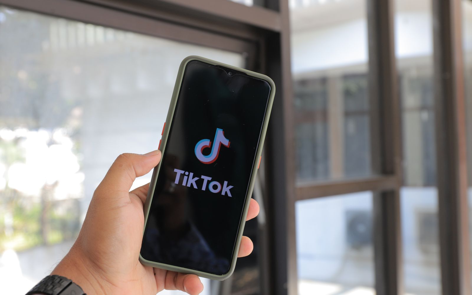 Mão segurando celular com o aplicativo do TikTok aberto