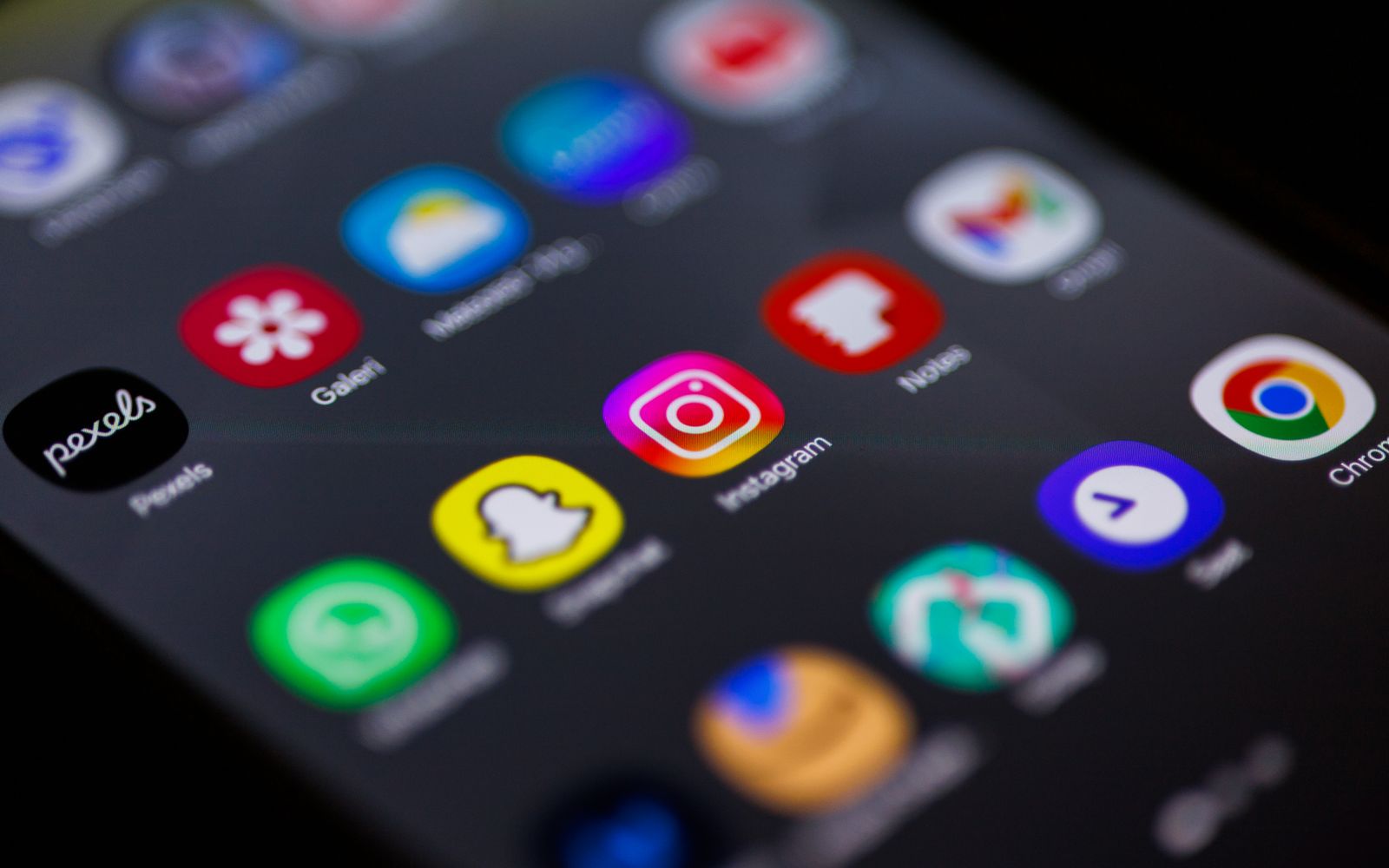 Visualização em close da tela inicial do smartphone com aplicativos populares como Instagram, Snapchat e Chrome