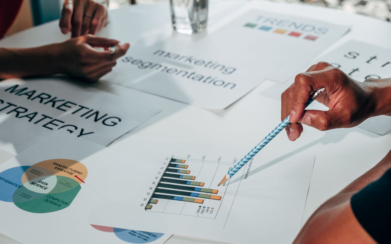 Equipe trabalhando em estratégia de marketing usando gráficos de dados e papéis em reunião de escritório