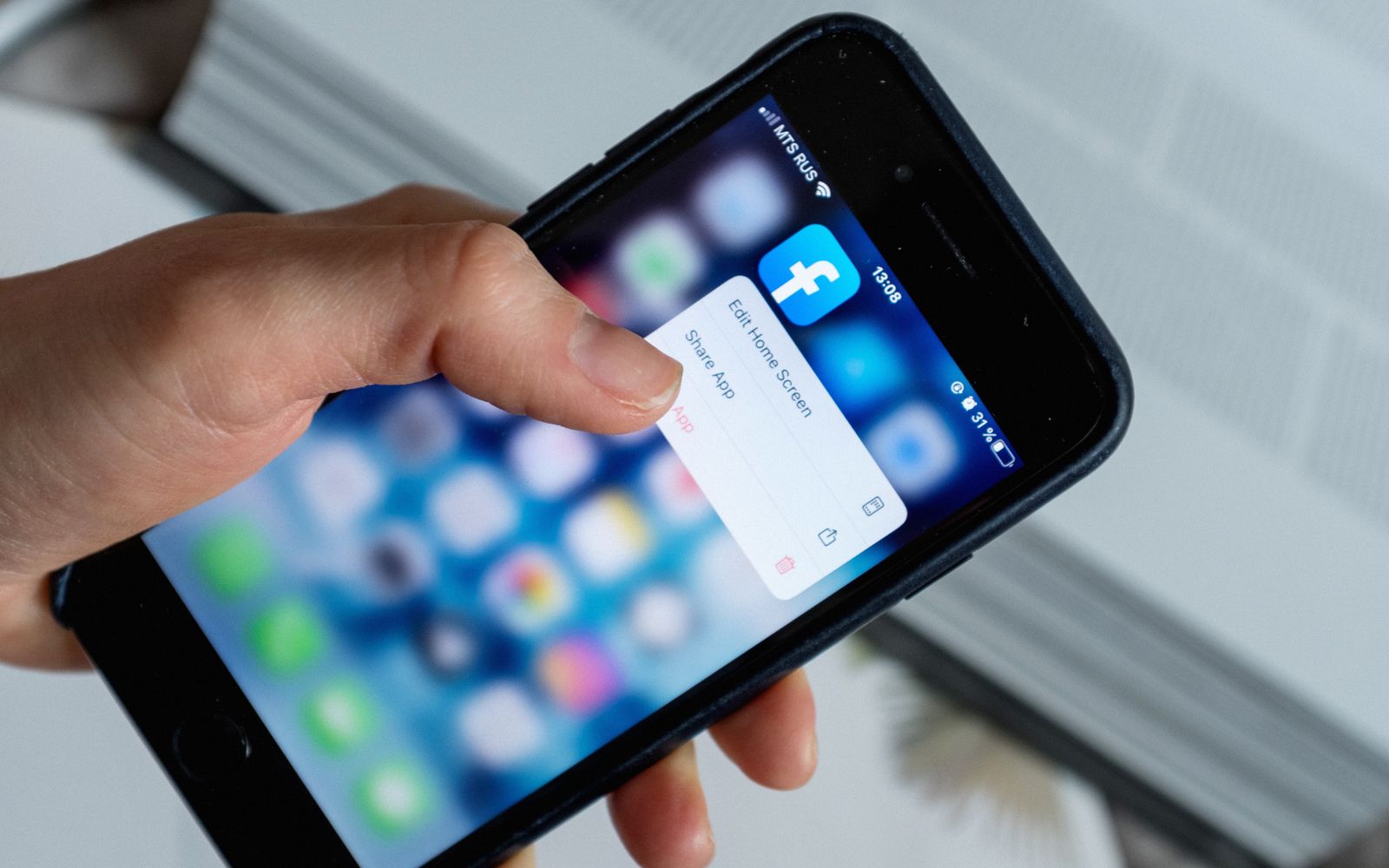 De cima de uma pessoa anônima tocando na tela borrada de um celular enquanto abre um aplicativo e escolhe uma opção de uma janela pop-up