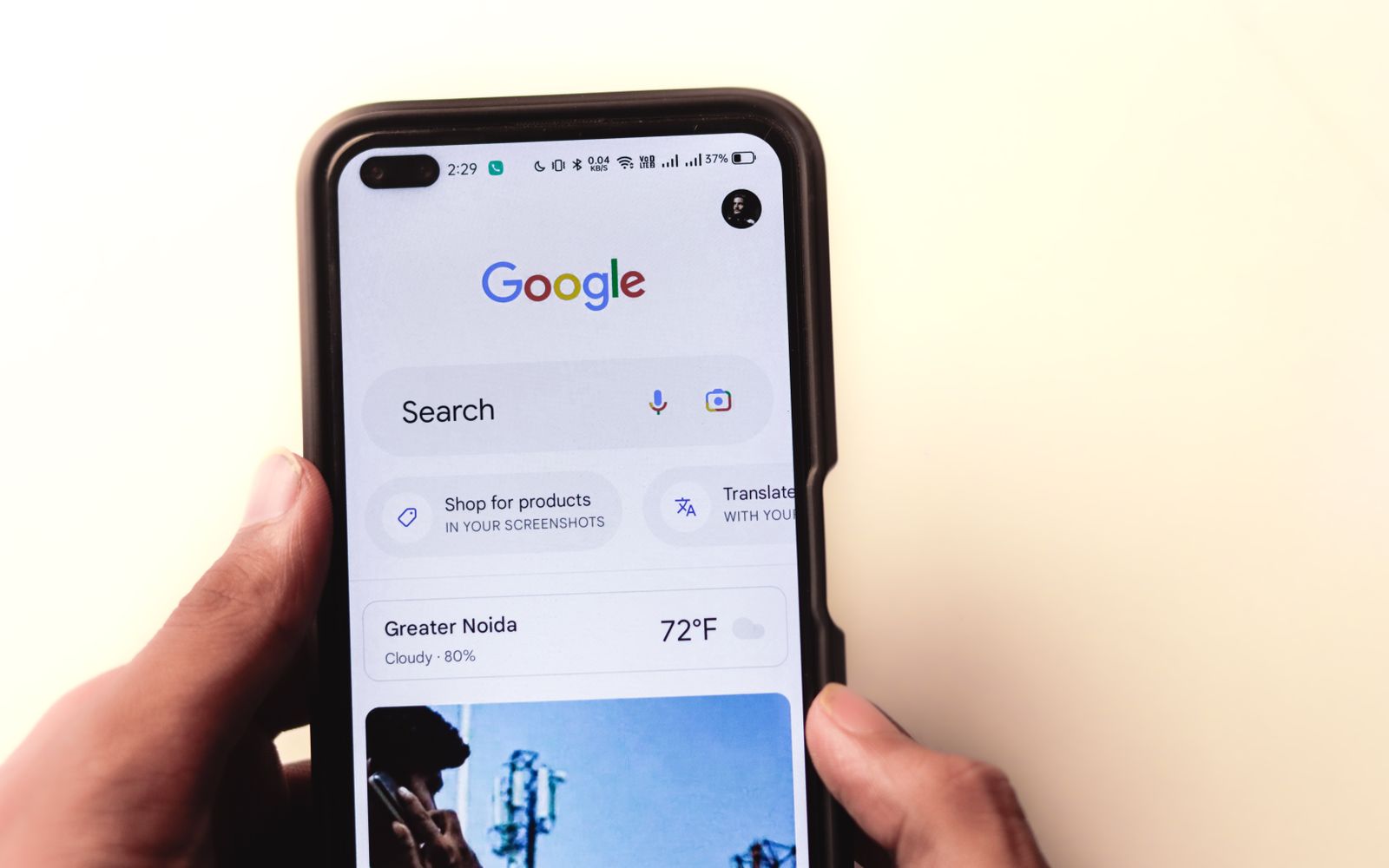 Mão segurando celular com a busca do Google na tela
