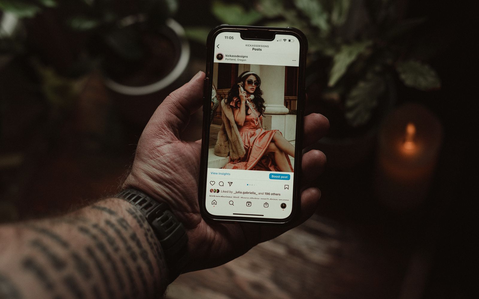 Mão tatuada segurando celular com uma publicação do Instagram
