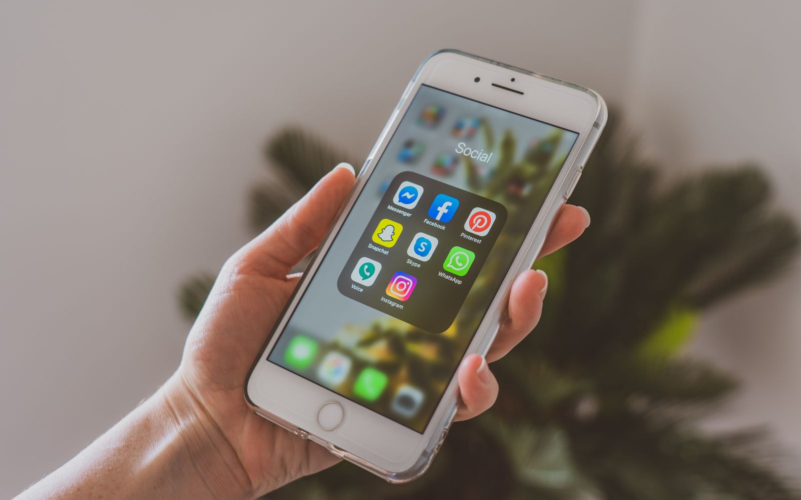 Mão segurando celular com os aplicativos de redes sociais na tela