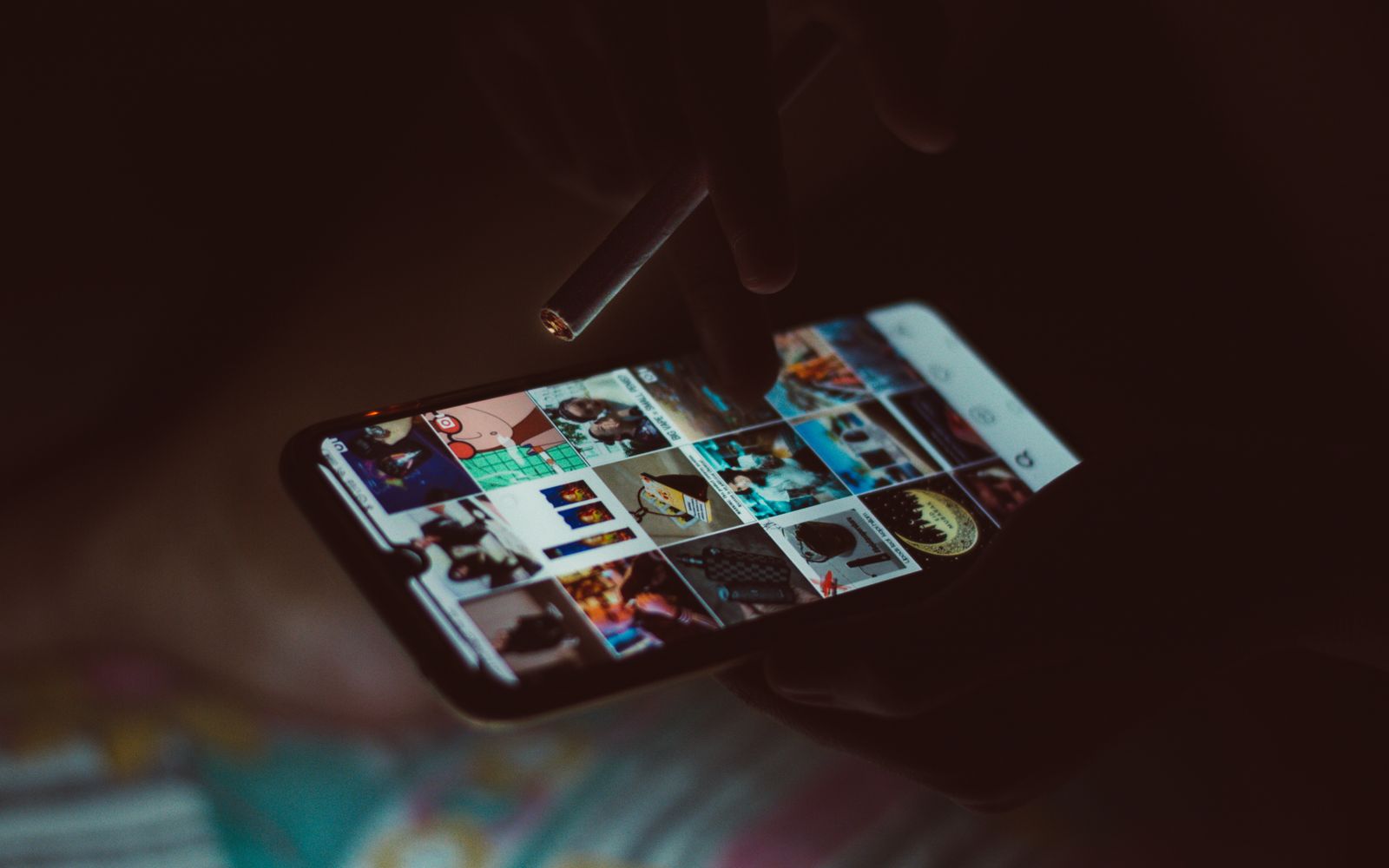 Uma mão segurando um smartphone e um cigarro, navegando por imagens
