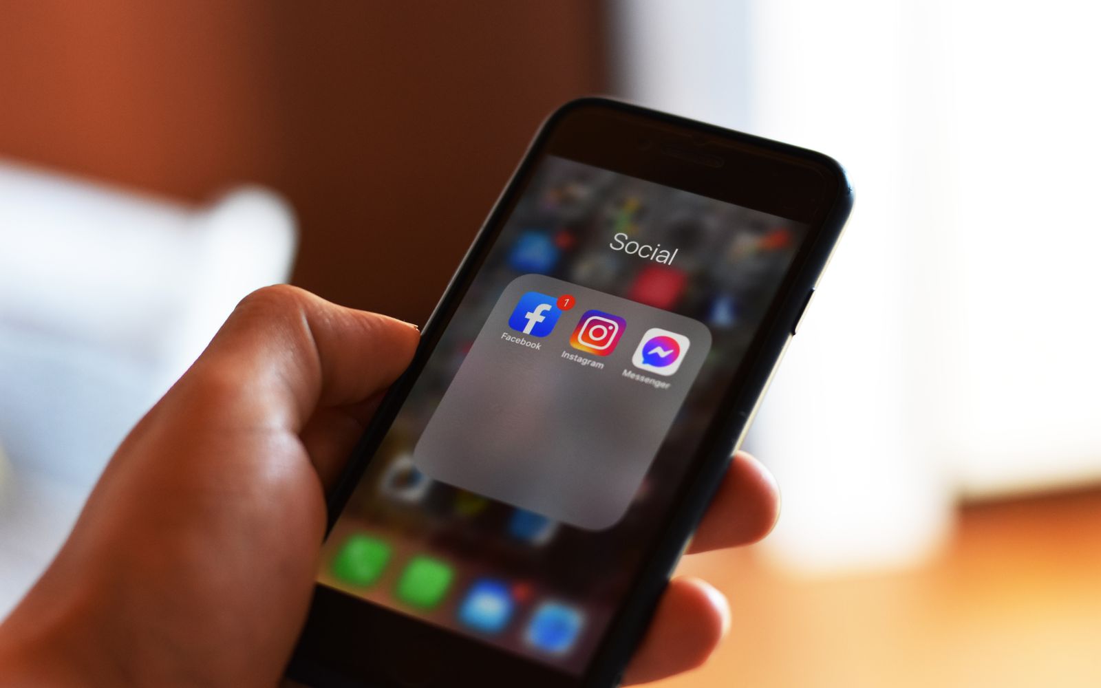 Mão segurando celular com os aplicativos de Facebook e Instagram