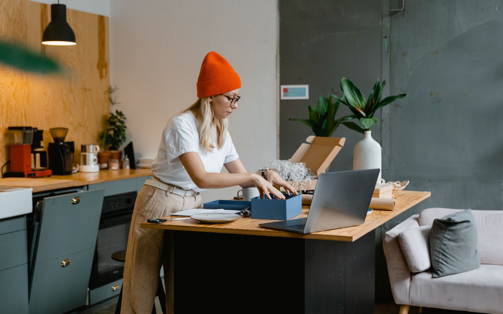 Jovem abrindo compras online em cozinha moderna, com o notebook aberto
