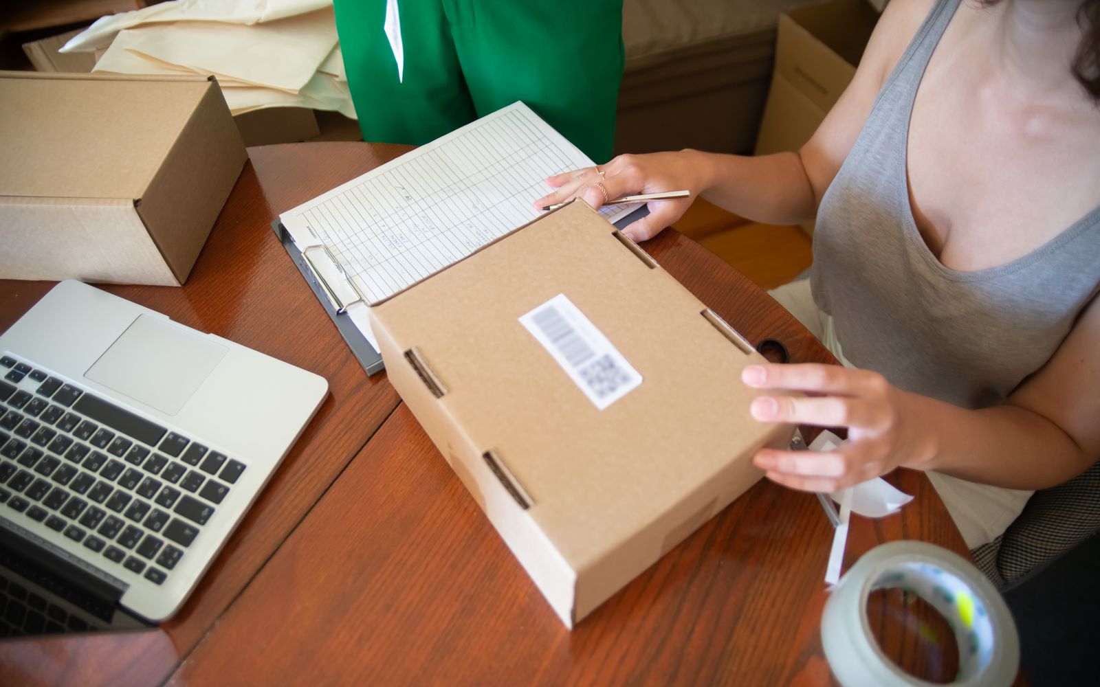 Duas pessoas embalando pedidos online em um pequeno negócio, com notebook