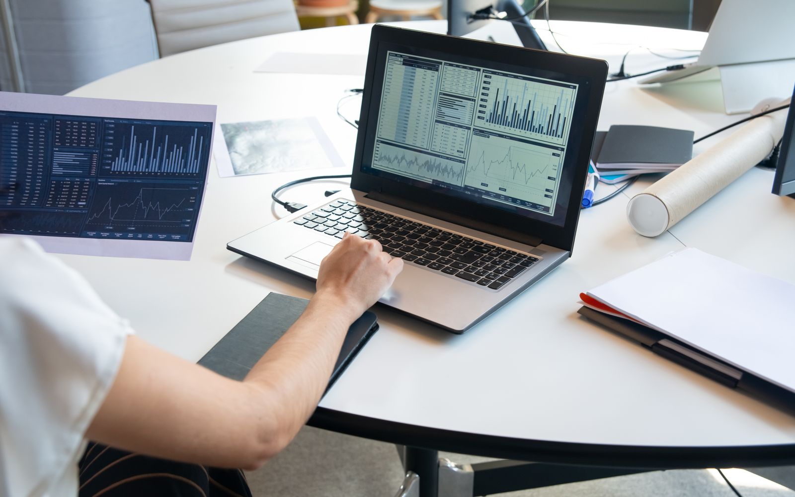 Profissional de negócios avaliando gráficos financeiros em um laptop em um ambiente de escritório moderno