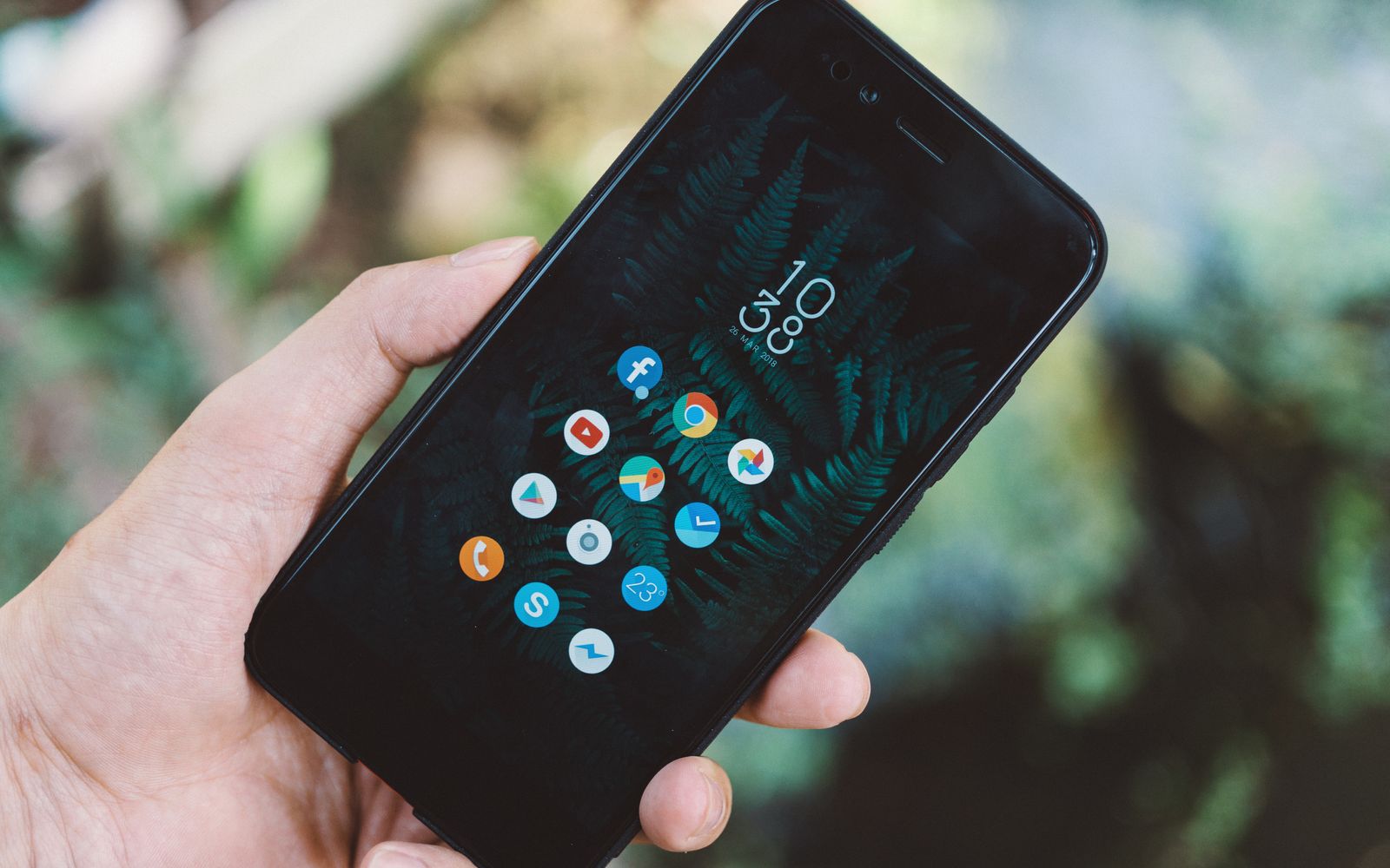 Mão segurando celular com os ícones dos aplicativos na tela