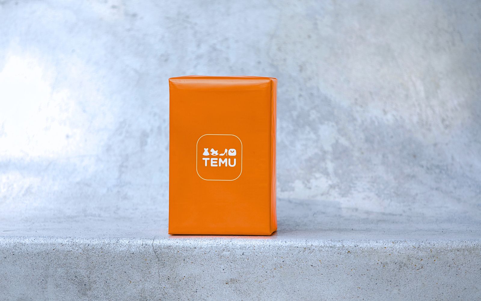 Encomenda laranja da Temu sobre superfície de concreto