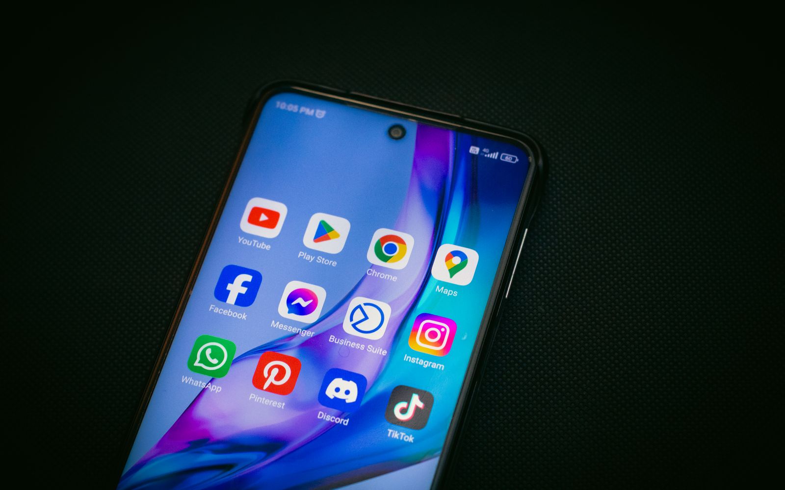 Tela de celular com os ícones de YouTube, Maps e TikTok sobre fundo preto