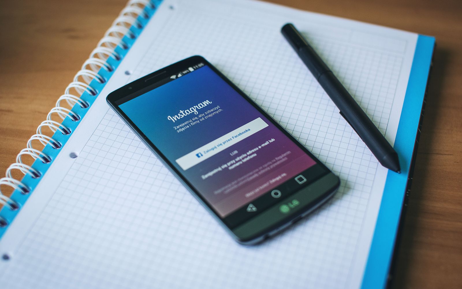 Celular exibindo o Instagram sobre um bloco de notas com caneta