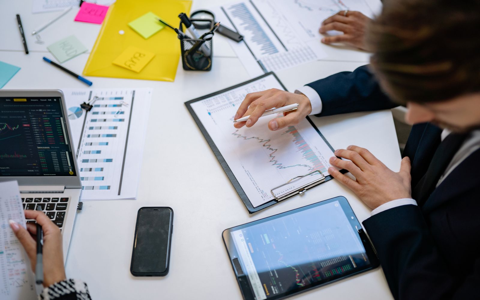 Equipe revisando gráficos financeiros e dados digitais em tablets em um ambiente de escritório
