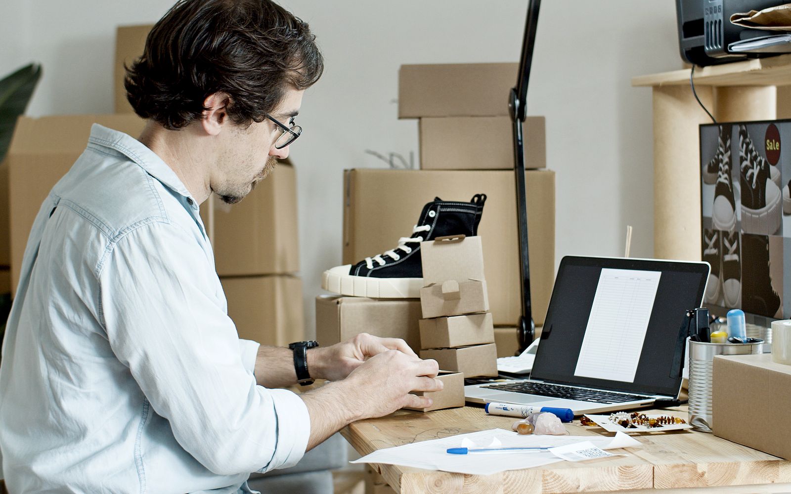 Homem embalando produtos e cuidando da loja virtual pelo notebook