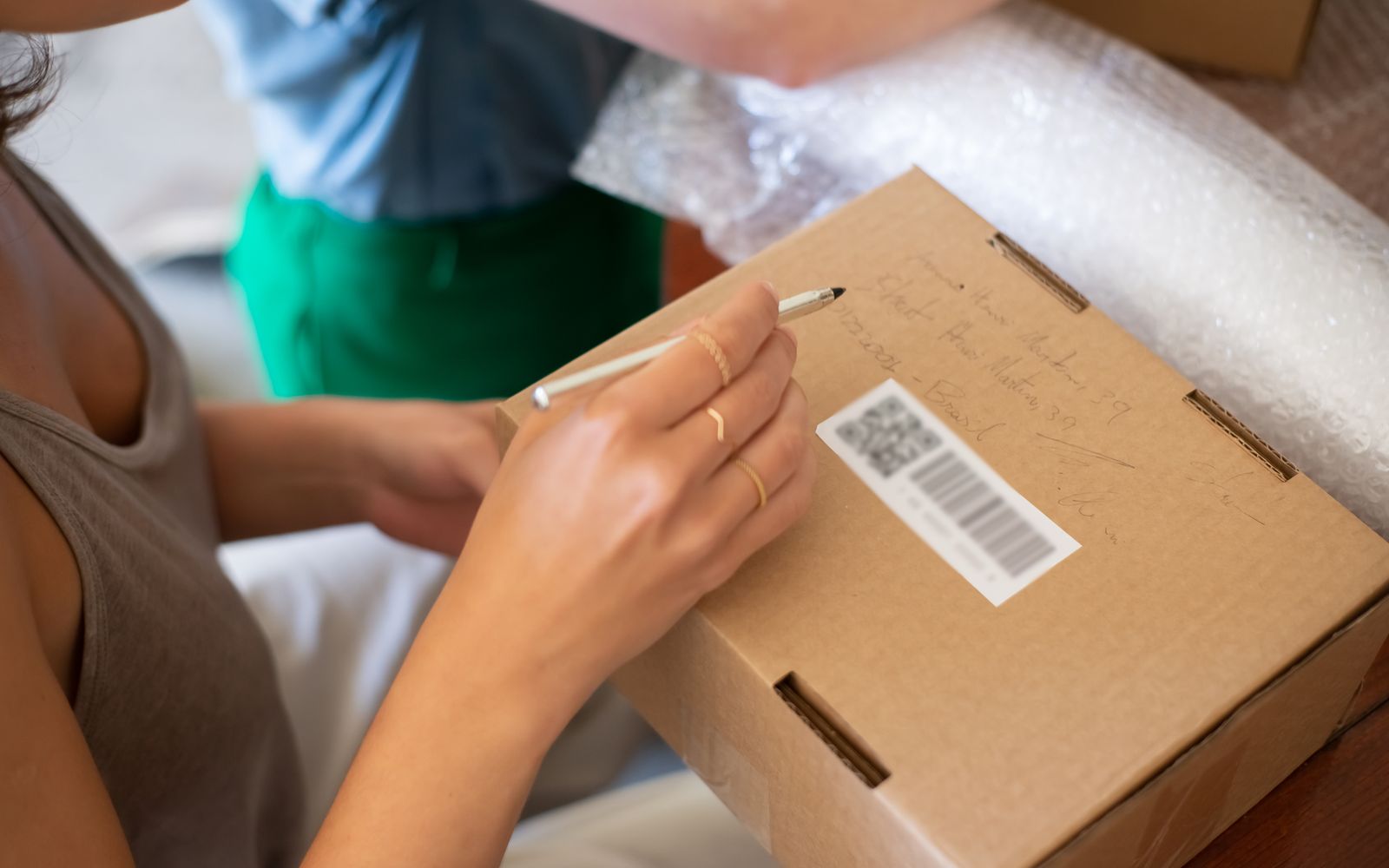 Mulher escrevendo em uma caixa de papelão para envio