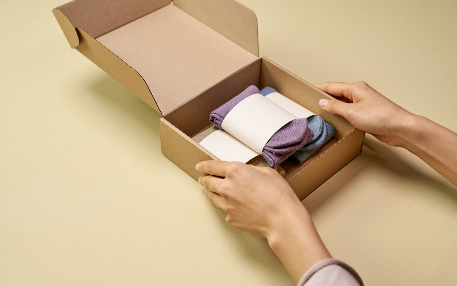 Pessoa colocando meias dobradas dentro de uma caixa de papelão
