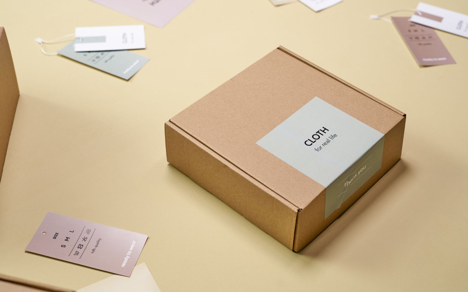 Embalagem de papelão com etiquetas de roupa sobre superfície clara