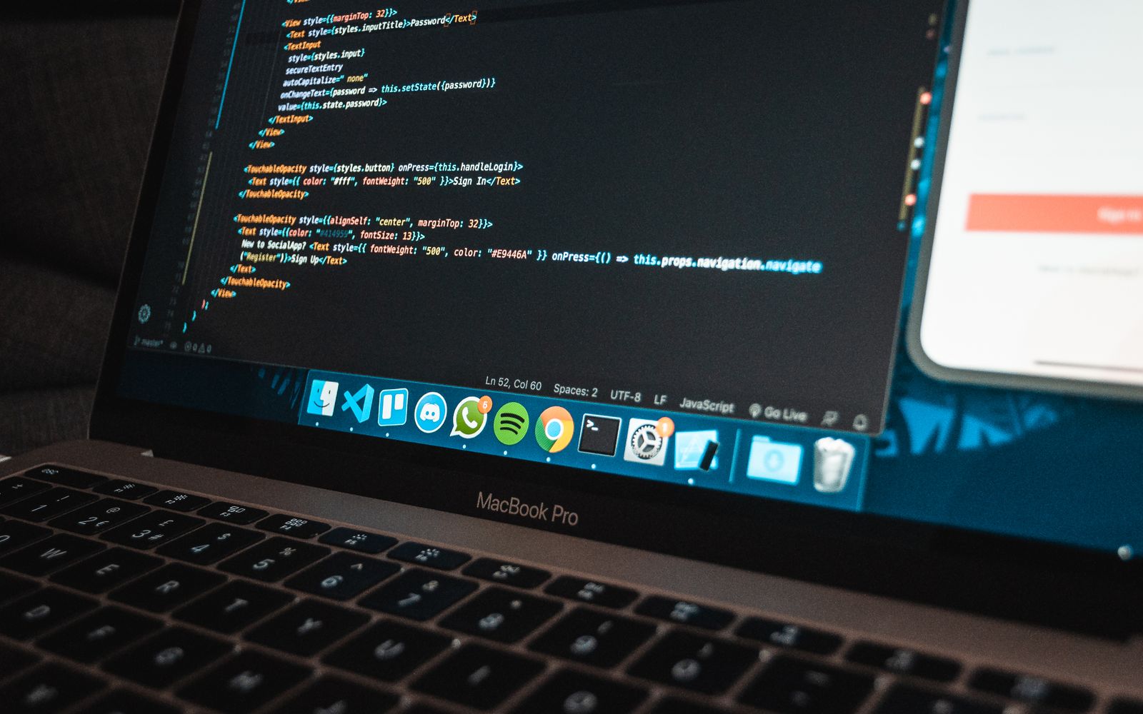Foto em close de um netbook com teclado e código na tela sobre uma mesa em um ambiente de trabalho