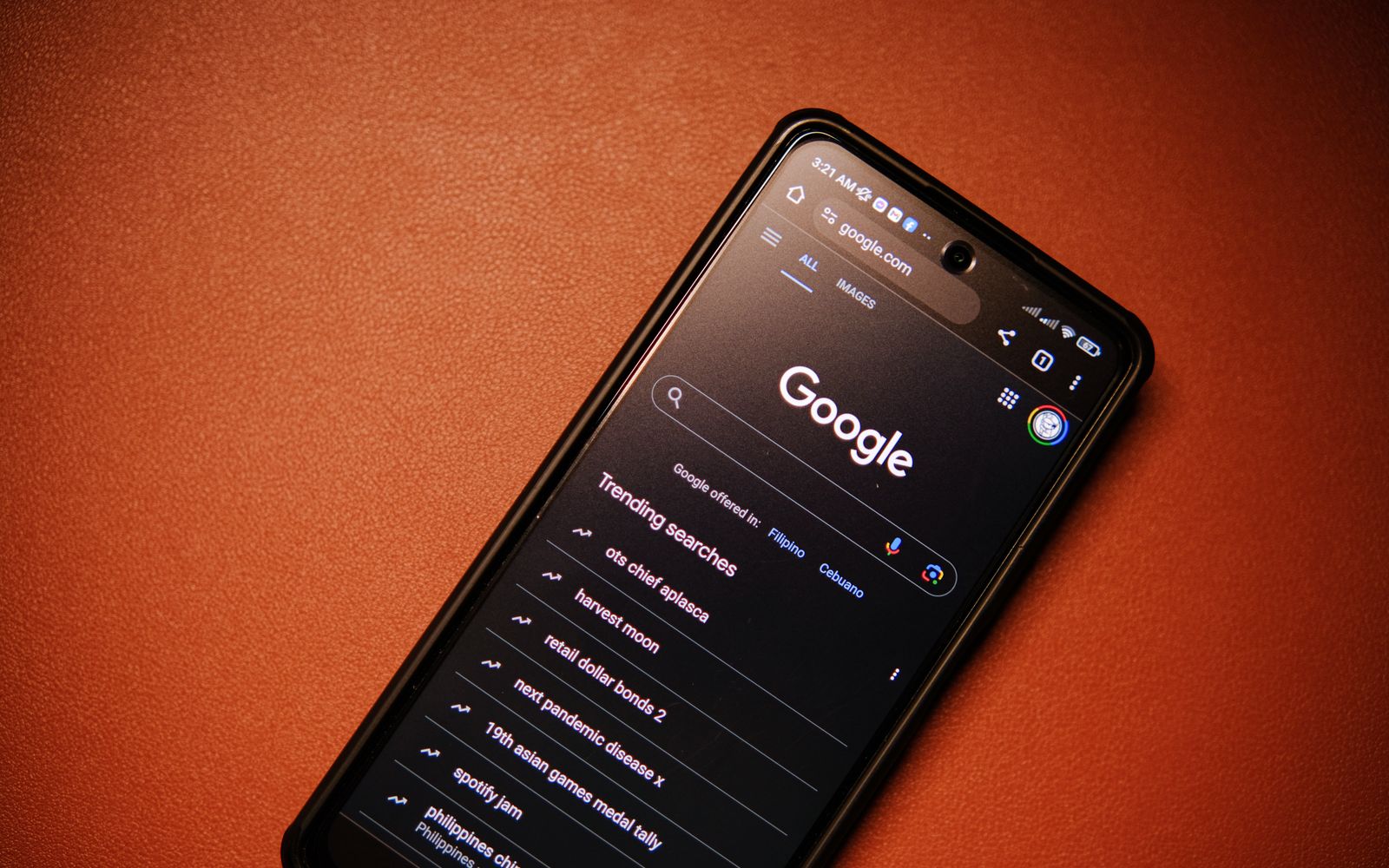 Celular sobre a mesa exibindo tendências de busca do Google, à noite