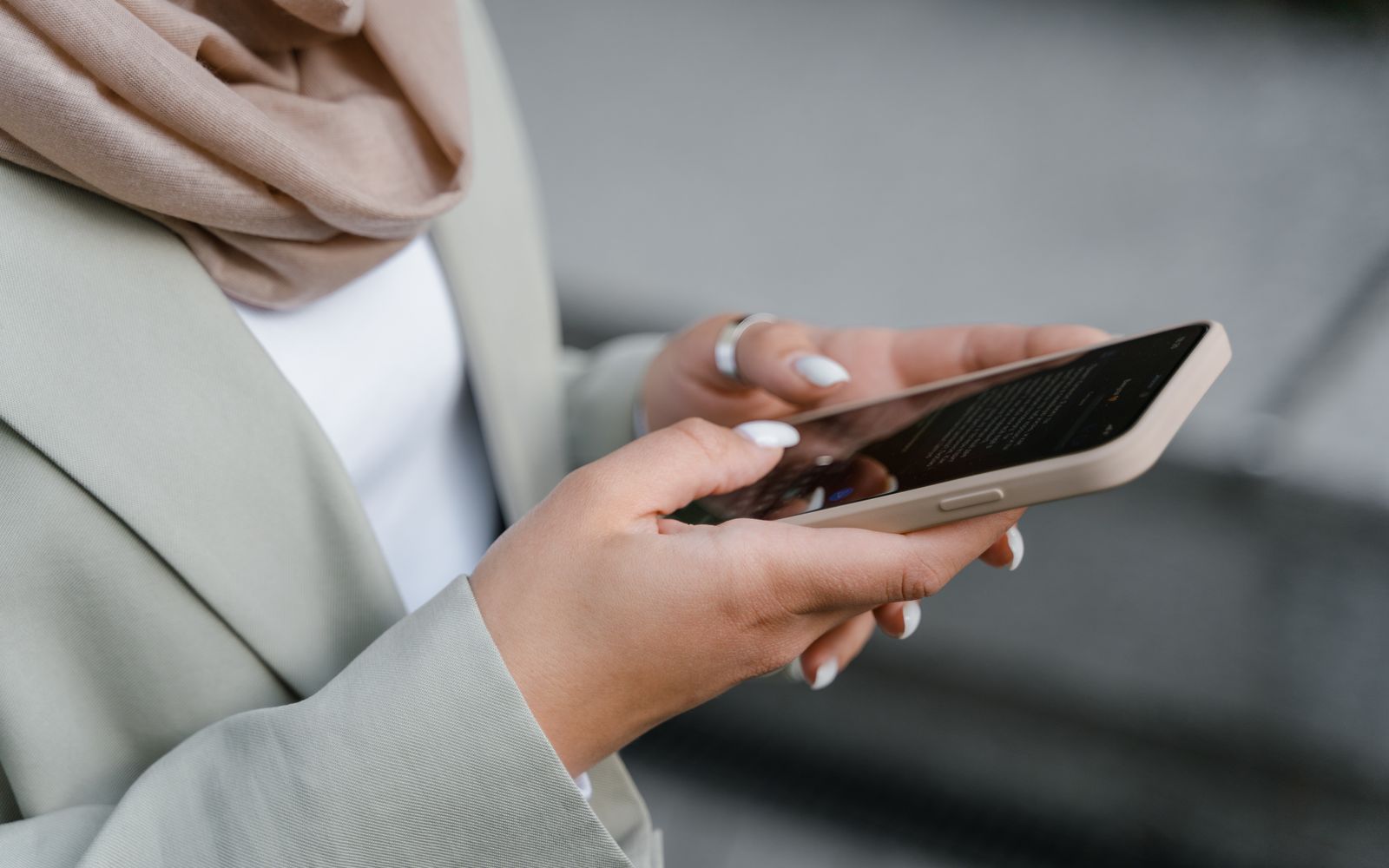 Mulher executiva de ternos cinza verificando mensagens no smartphone ao ar livre