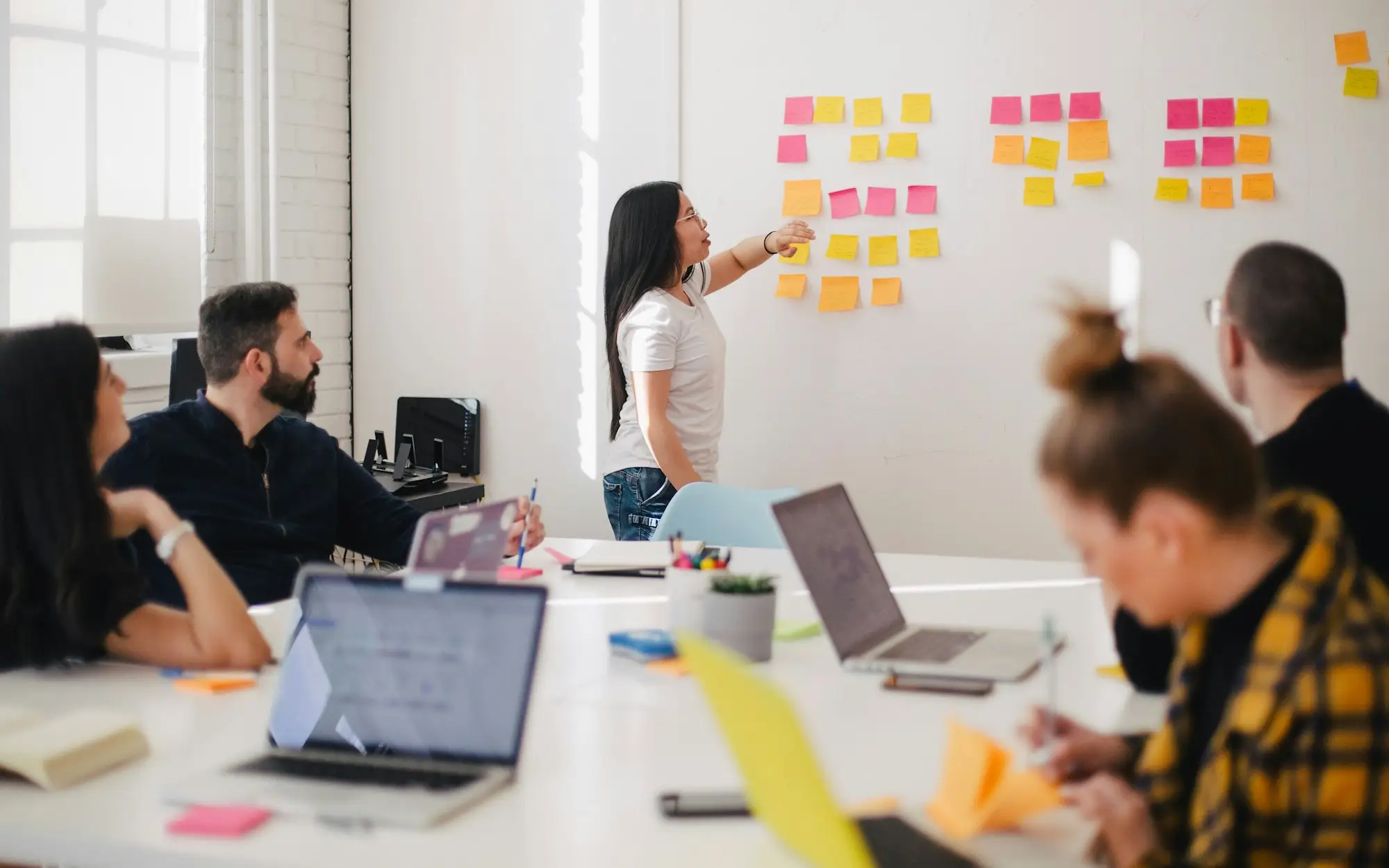 Equipe reunida em frente a um quadro de post-its